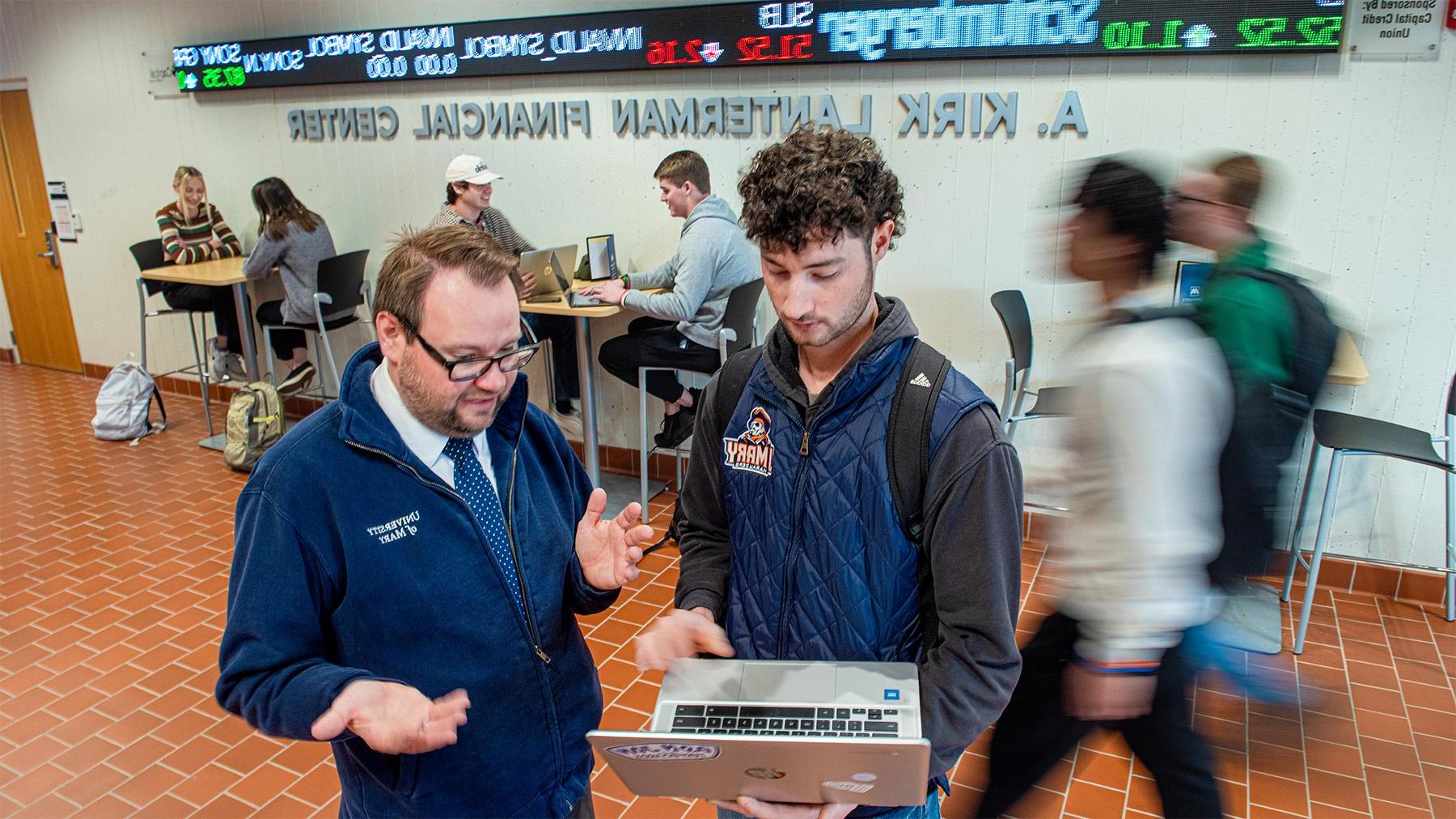 Student working with a profesor in the School of Business Hallway